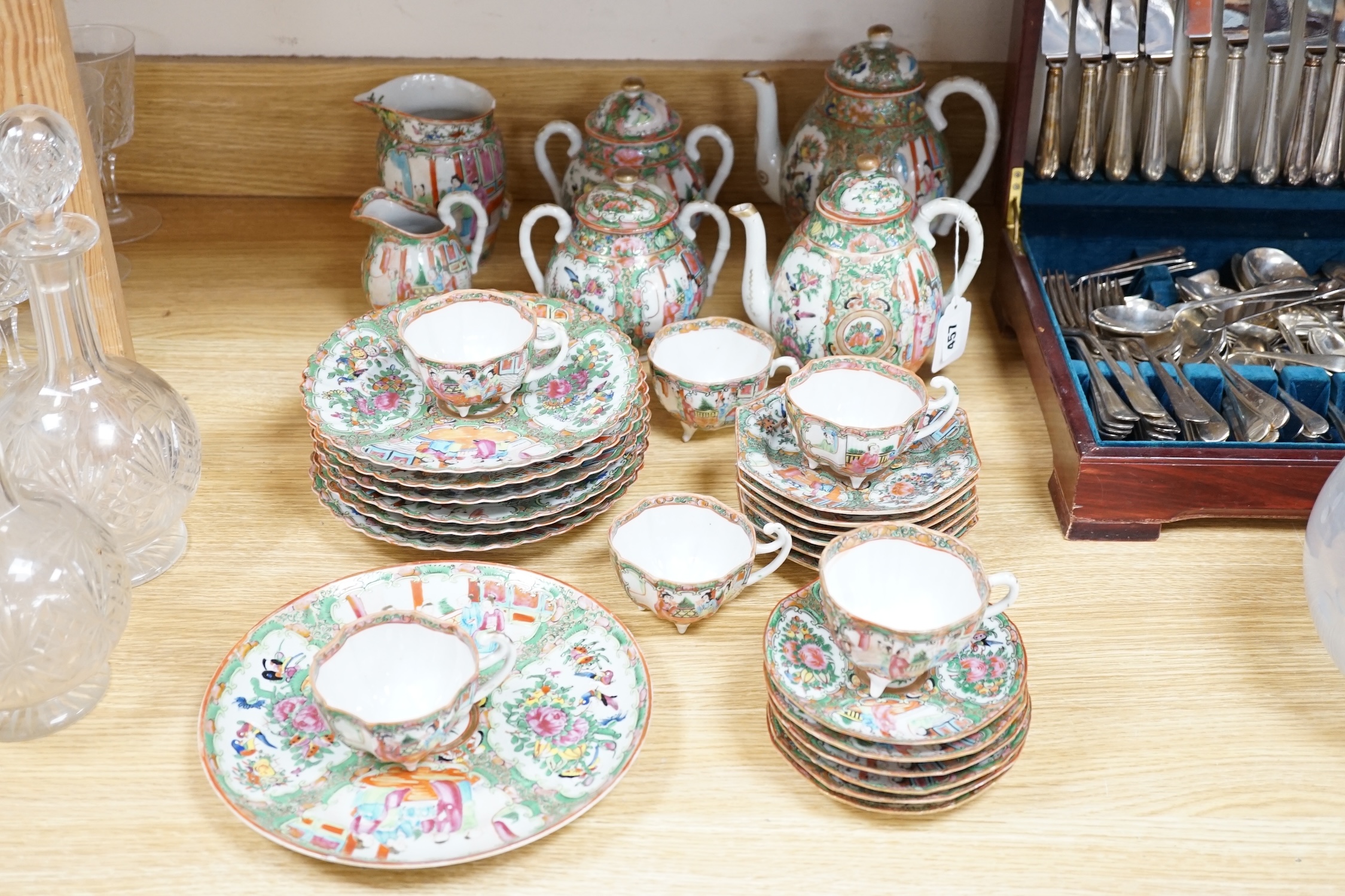 A Chinese famille rose six place setting tea service, including a large tea pot and cover, a smaller water pot and cover, two sugar bowls with covers, a large milk jug (handle broken) a small cream jug and a cake plate,(